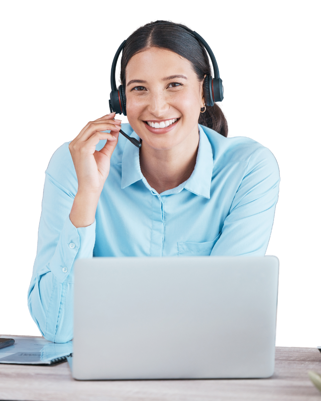 Vrouw met donker haar in een lichtblauw overhemd, met headset op, glimlachend achter een laptop.