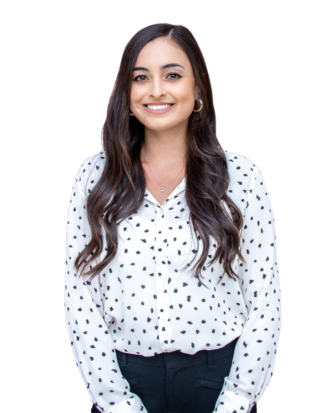Vrouw met lang golvend donker haar, in een witte blouse met zwarte stippen, glimlachend recht naar de camera.