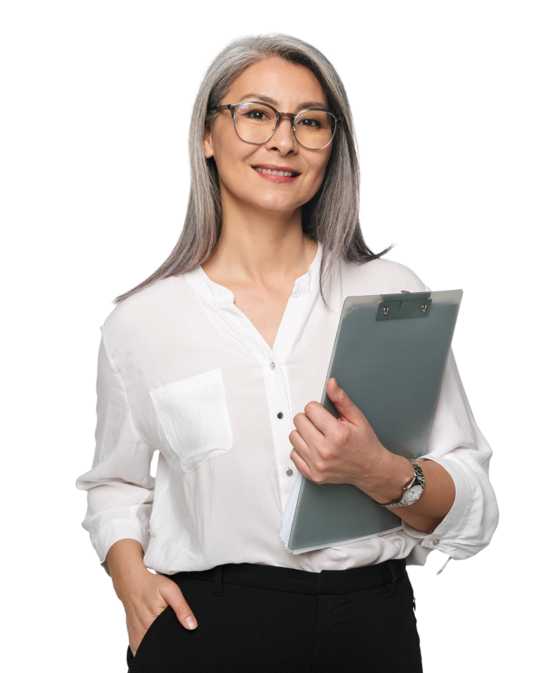 Vrouw met schouderlang grijs haar en ronde bril, in een witte blouse, staand met één hand in haar broekzak en de andere hand om een grijs clipboard, vriendelijk glimlachend.