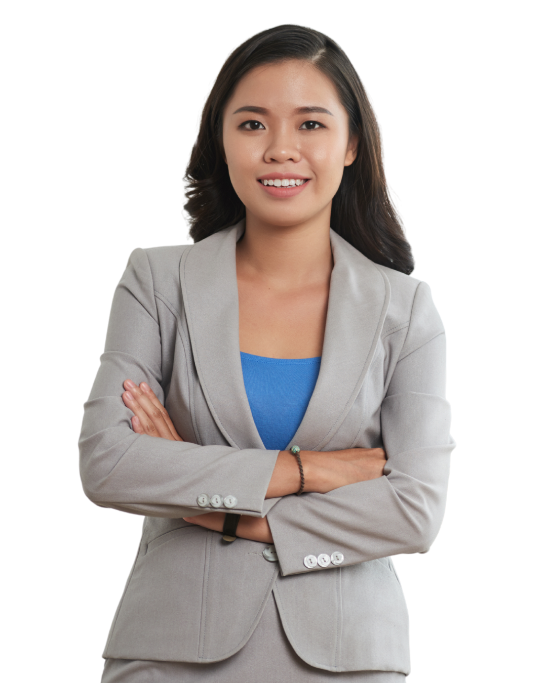 Meisje heeft zwart haar en draagt een grijze blazer. Daaronder draagt ze een blauw shirt. Heeft haar armen over elkaar heen en lacht.